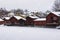 Row of red wooden huts with snowfall