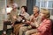 Row of senior friendly men and women sitting on sofa and playing video game