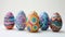 A row of seven vibrant, intricately decorated Easter eggs displayed on a textured surface