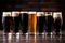 row of six different stout beers in pint glasses