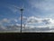 Row of six wind turbines in a blue sky with cottony clouds