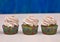 A row of spinach-mint cupcakes with fruit jam and berry cream on top