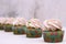 A row of spinach-mint cupcakes with fruit jam and berry cream on top