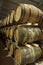 A row of stacks of traditional full whisky barrels, set down to mature, in a large warehouse