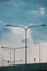 A row of street lights/lamps silhouetted against a blue sky. LED road lighting. Road lighting poles. A lot of road lanterns