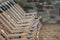 A row of suspended empty deck chairs in rows lined up in order on the beach in the sand