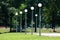 Row of tall street lamps made of white ball like plastic sphere mounted on top of metal poles in local public park