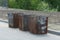 A row of three old iron open trash cans in brown rust