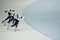 Row of three young active athletes on skates sliding along ice rink