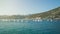 Row of training sailboats on a tugboat is passing by the hilly seashore