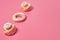 Row of two homemade baked buns in form of rose and donut powdered of sugar on pink background