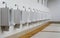 A row of urinals in tiled wall in a public restroom.