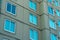 Row of visible blue glass windows with beige stucco exterior on side of building late afternoon shade