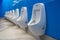 Row of white clean urinals in public restroom