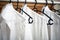 Row of white cotton clothes hang on black hangers on a rack Close-up. white blouse