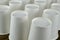 Row of white disposable eco friendly paper cup for coffee or hot beverage on dark backdrop. Selective focus