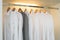 Row of white and grey shirts in white wardrobe