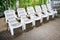 Row of white plastic outdoor chairs with backrest by swimming po