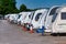 A row of white touring caravans on hardstanding in a secure caravan storage facility
