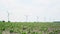 A row of wind turbines with a potato field and a highway