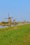 A row of windmill in kinderdijk with large visible area of green grass field