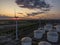 Row of windmills generating green electricity at sunset in industrial harbour area with silos