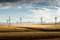 A row of windmills with power lines under a dramatic sunset sky near Pincher Creek Alberta Canada