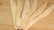 Row of wooden knives on cutting board surface. Wooden eco-friendly disposable tableware rotate. Disposable ecological
