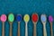 A row of wooden spoons with colored powder on blue stones