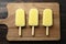 Row of Yellow Ice Lollies on Wood from Above