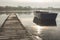 A rowing boat floats adrift on a frozen lake beside an empty walkway