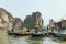 Rowing boats harbour and boat stop with many boats floating over emerald water with limestone islands in background in summer.