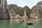 Rowing boats with many tourists traveling inside limestone cave with limestone island in background in summer at Quang Ninh.