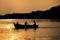 Rowing wooden boat near forest in late evening during sunset people silhouettes