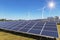 Rows array of polycrystalline silicon solar panels and wind turbines generating electricity in hybrid power plant systems station