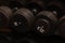 Rows of black iron dumbbells on a rack in gym, black