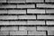 The rows of bricks ready for transport over the wire fence of the store. Background. Black and white image.