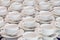 Rows of clean white coffee or tea cups, dish and spoon in a cafeteria or restaurant ready to serve a hot beverage