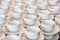 Rows of clean white coffee or tea cups, dish and spoon in a cafeteria or restaurant ready to serve a hot beverage