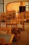 Rows of empty chairs and tables of hte warm sunlit empty cafe / restaurant. Cafe interior