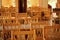 Rows of empty chairs and tables of hte warm sunlit empty cafe / restaurant. Cafe interior