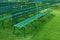 Rows of empty green outdoor benches on grass
