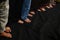 Rows of feet of men standing on black carpet