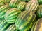 Rows of fresh green striped watermelons piled on the market counter