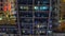 Rows of glowing windows with people in apartment building at night.