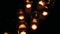 Rows of hundreds burning votive candles in dark moody sacral environment, background texture