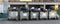 Rows of many big metal overloaded dumpster cans full of black plastic trash litter bags near residential building at