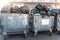 Rows of many big metal overloaded dumpster cans full of black plastic trash litter bags near residential building at