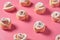 Rows of many homemade baked buns in form of rose spangled of powdered sugar lies on pink background