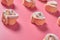 Rows of many homemade baked buns in form of rose spangled of powdered sugar lies on pink background